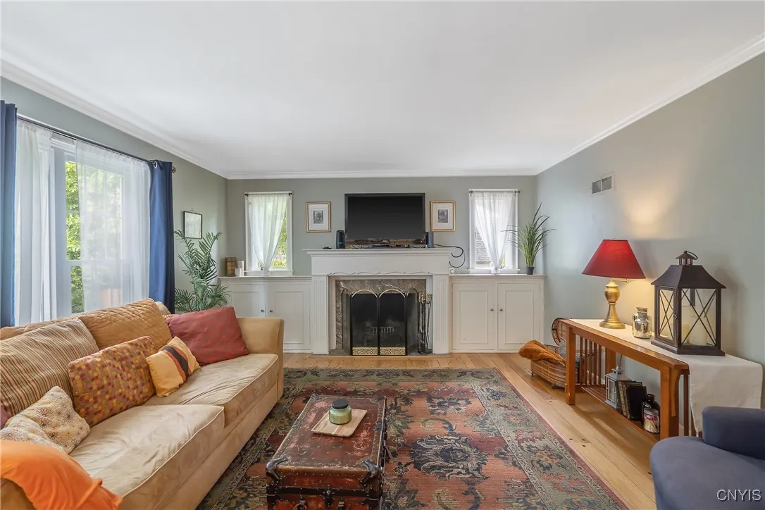 The marble-faced fireplace with traditional mantle flanked by built-in cabinets and tall windows above is visually pleasing as well as extremely functional!