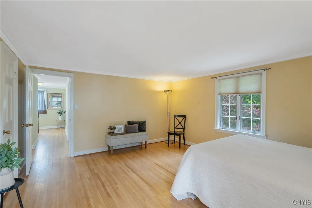 Now at the far end of the hall, the primary bedroom sits at the opposite rear corner of the home looking out over the greenery of the backyard tree canopy.