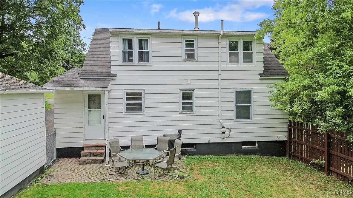 And now let us explore the grounds.  Exiting from the kitchen through the pedestrian door brings us to an adorable brick-paver patio.  Dining al fresco is a snap with space for a table & chairs, plus a BBQ.