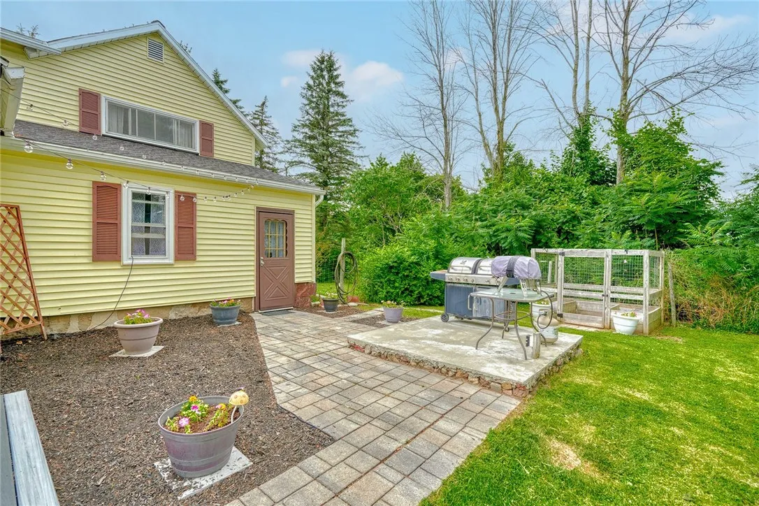 View of the back of the home with paver walkway and vegetable garden.