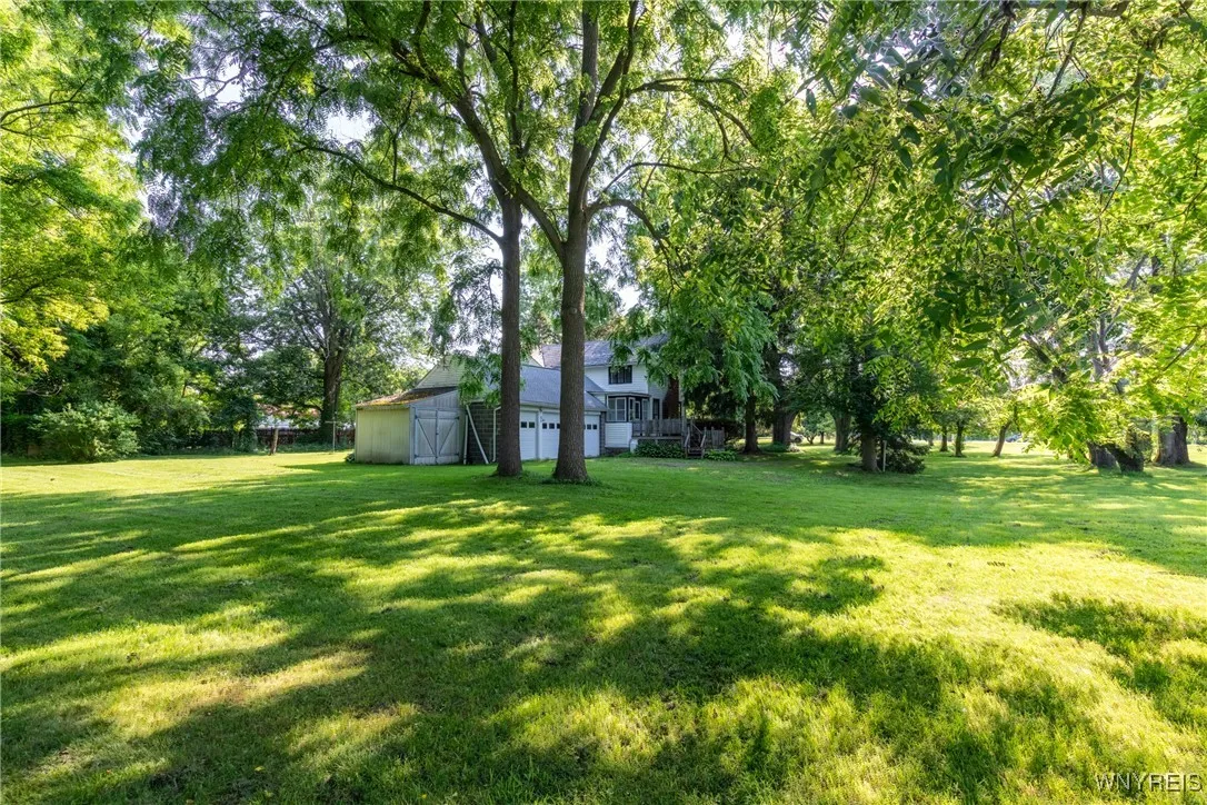 This view shows the smaller deck leading to the side entryway, the 3 car attached side load garage and attached shed,