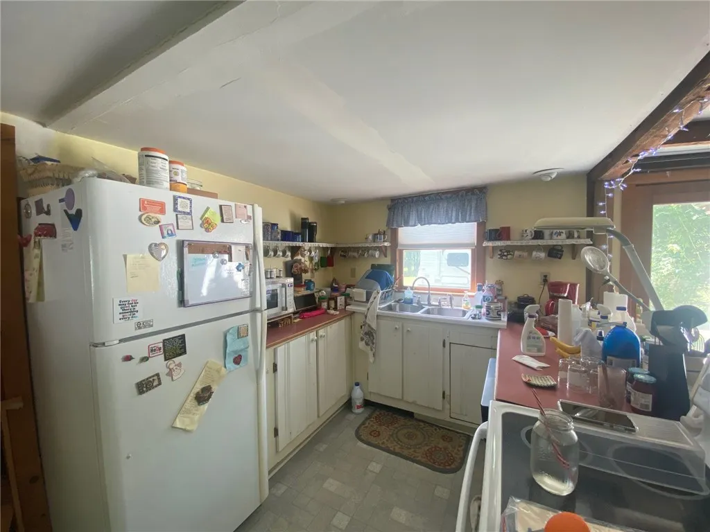 Quaint kitchen with open shelving and back door access to potential garden.