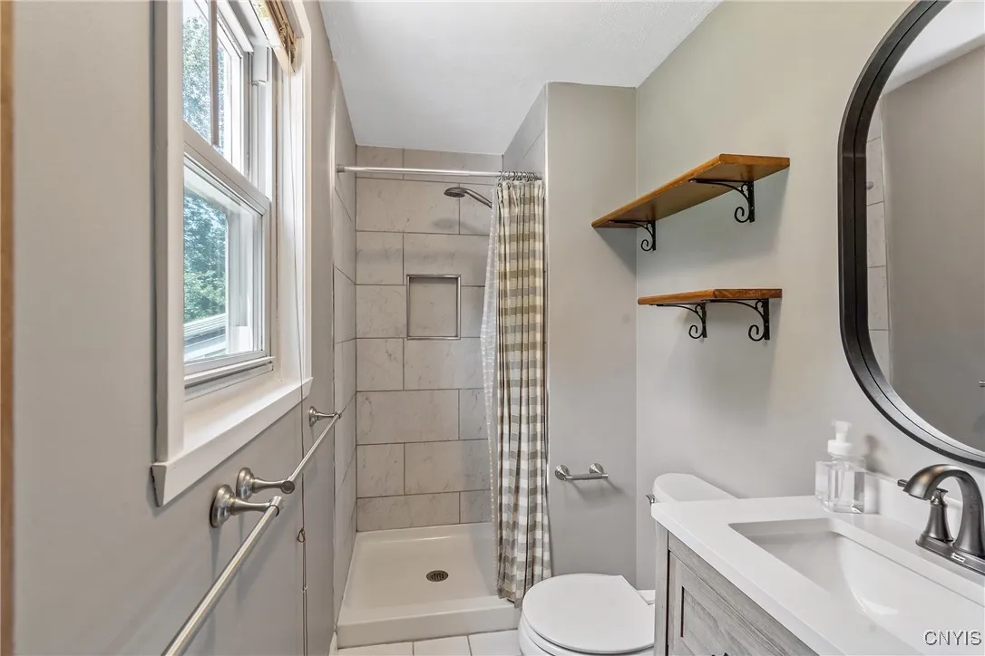 Echoing the home\'s thoughtful updates, the en suite bath features a stylish new vanity, walk-in shower, and decorative shelving that adds both charm & function.