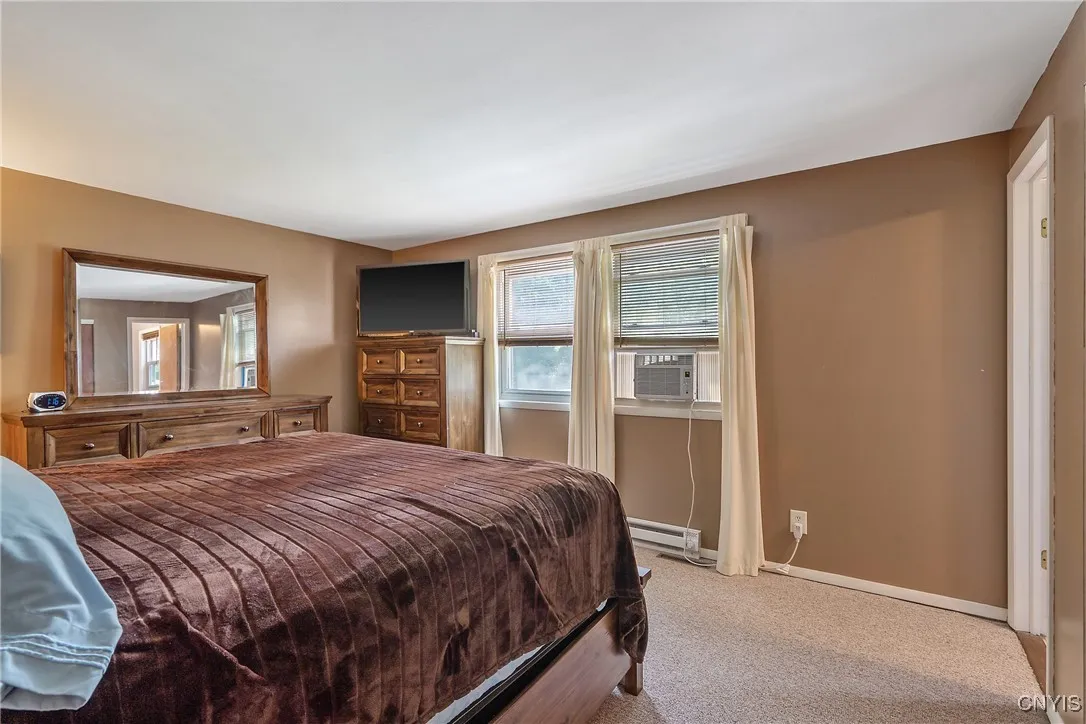 Tucked at the back of the home, this bedroom offers peaceful views of the yard through two bright windows—perfect for catching a fresh breeze or enjoying a cooler sleeping space with added A/C.