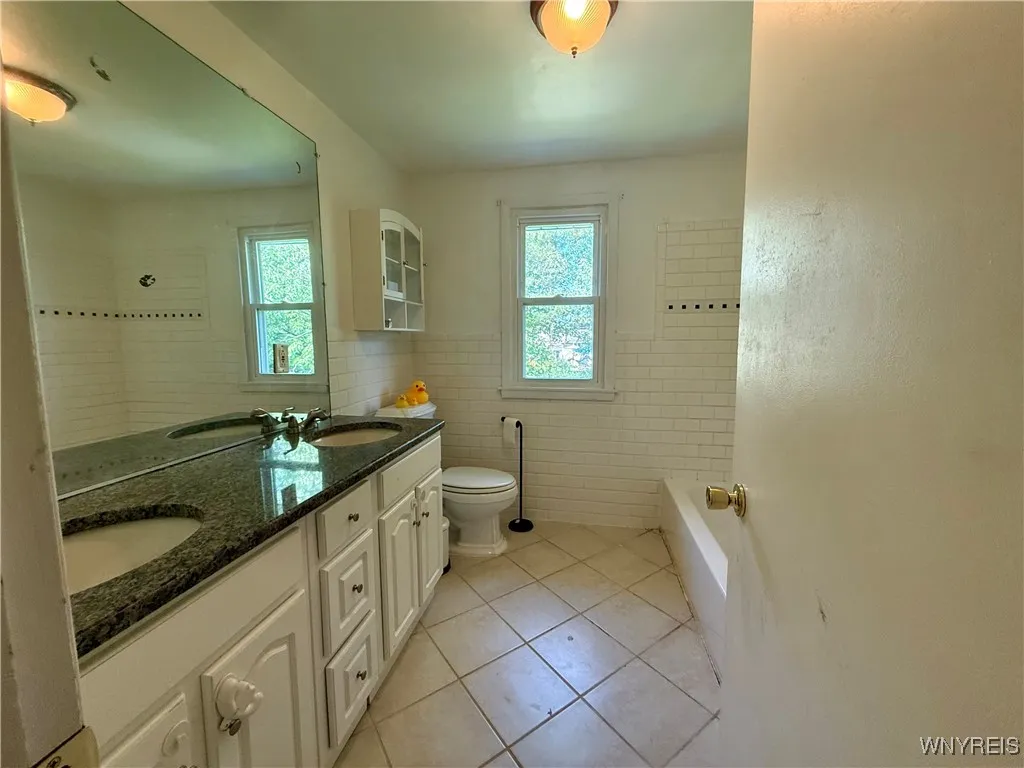 Full bath with double sinks, granite counters, ceramic floors