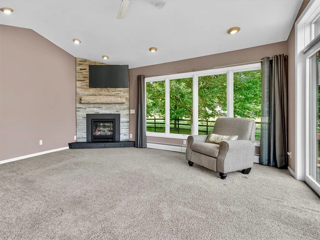 Large great with high ceilings, gas fireplace, and sliding glass doors to spacious deck