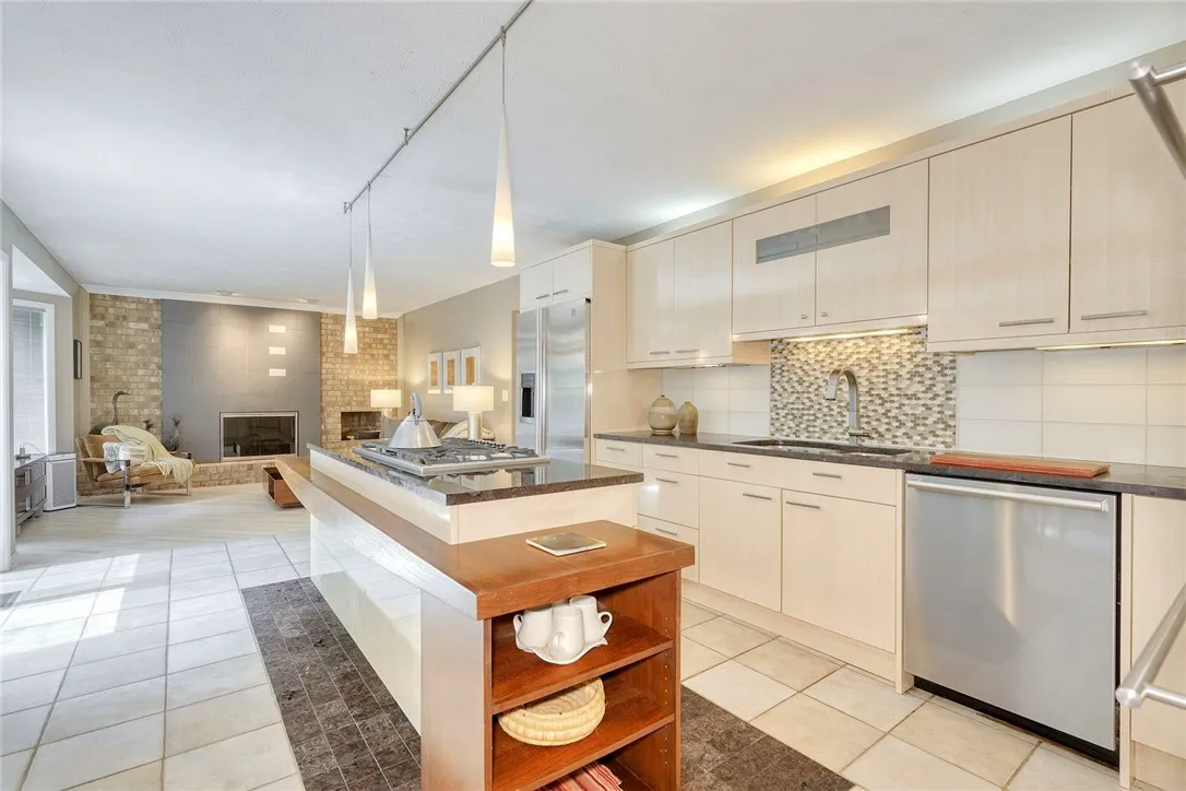 UPDATED DESIGNER KITCHEN with statement island, gas cooktop, granite counters, tile backsplash, quality cabinetry, and bright eat-in nook overlooking backyard.