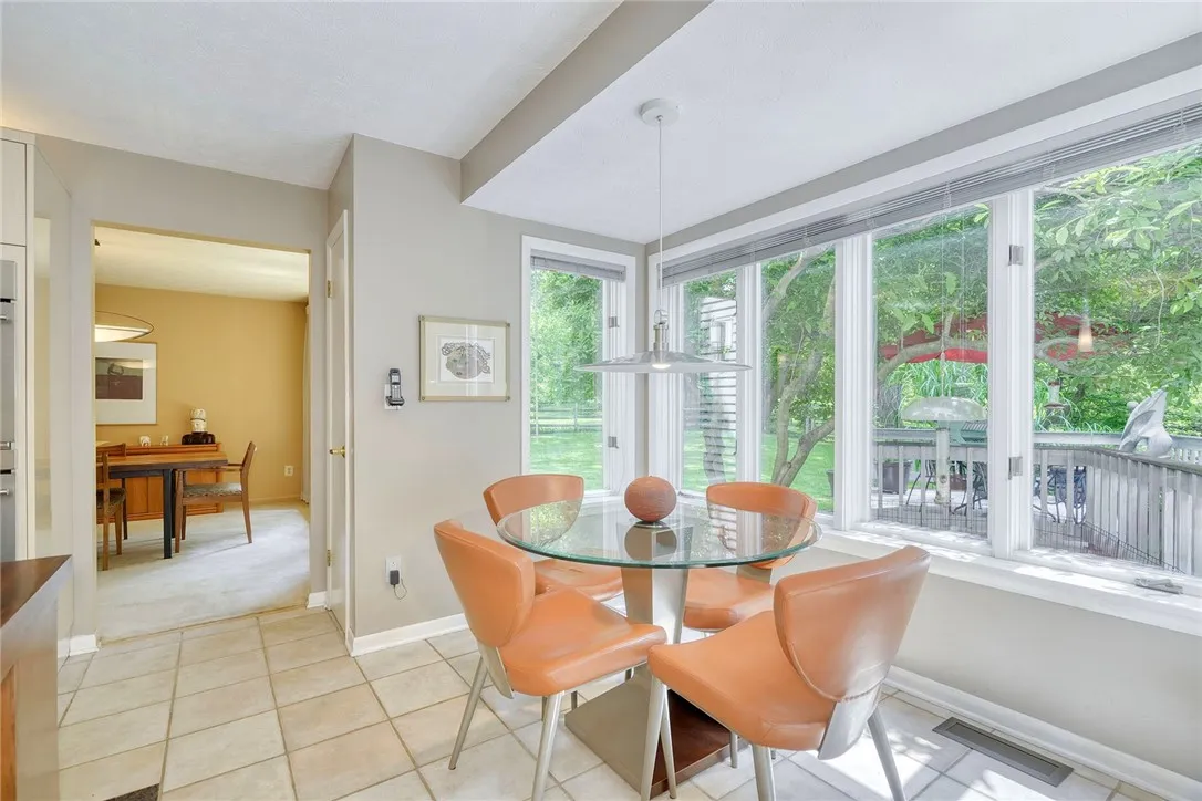 UPDATED DESIGNER KITCHEN with statement island, gas cooktop, granite counters, tile backsplash, quality cabinetry, and bright eat-in nook overlooking backyard.