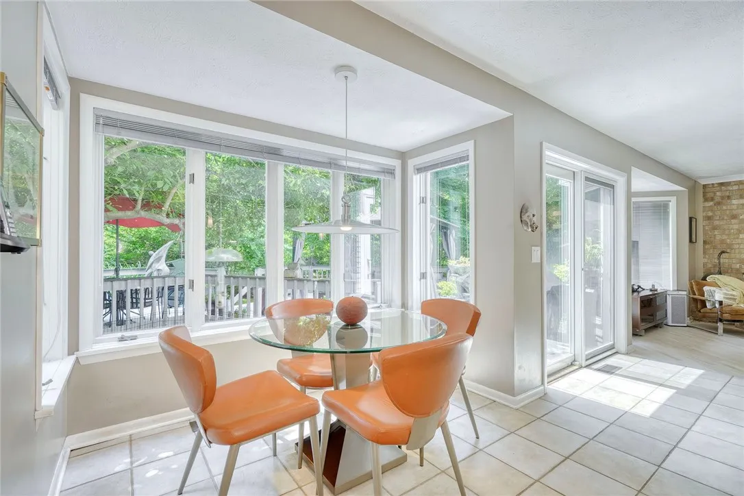 UPDATED DESIGNER KITCHEN with statement island, gas cooktop, granite counters, tile backsplash, quality cabinetry, and bright eat-in nook overlooking backyard.