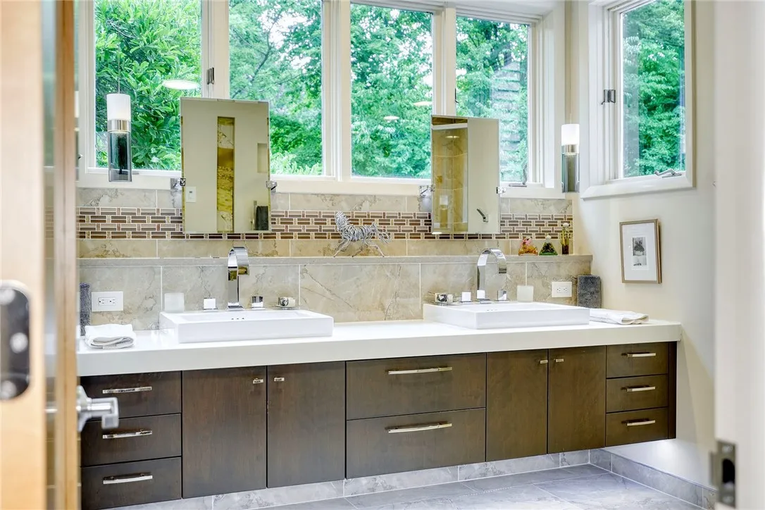 Remodeled Spa-Like en suite with heated porcelain tile, floating double vanity with underlighting, curbless shower, rainfall head + body jets. Windows wrap the vanity, bringing in natural light + treetop views