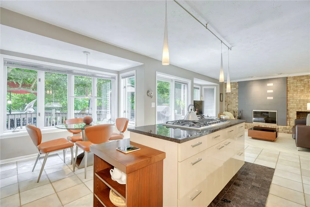 UPDATED DESIGNER KITCHEN with statement island, gas cooktop, granite counters, tile backsplash, quality cabinetry, and bright eat-in nook overlooking backyard.
