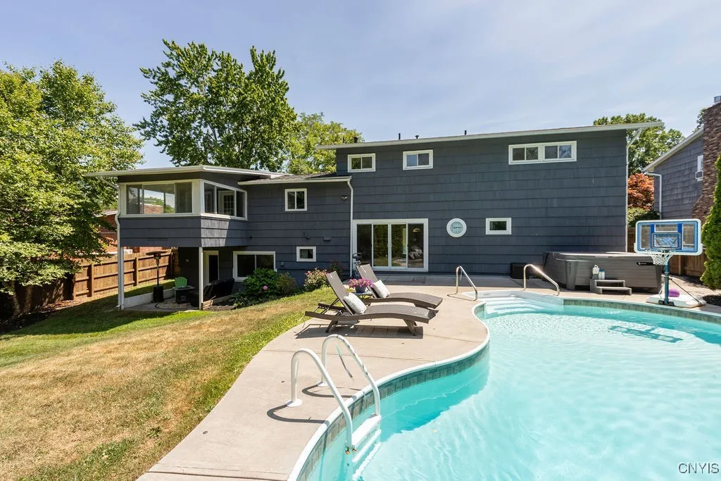 This view of the backside of the house shows a walk out basement door beneath the elevated sunroom. There are  full-sized windows for the family room located just inside that walk in access to the lower level of the home.