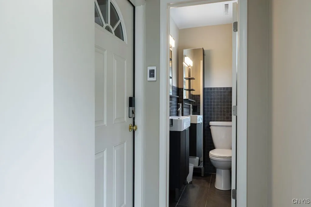 Half bath located at back of foyer, next to garage entry and sliding glass doors to pool and yard.  Very convenient!