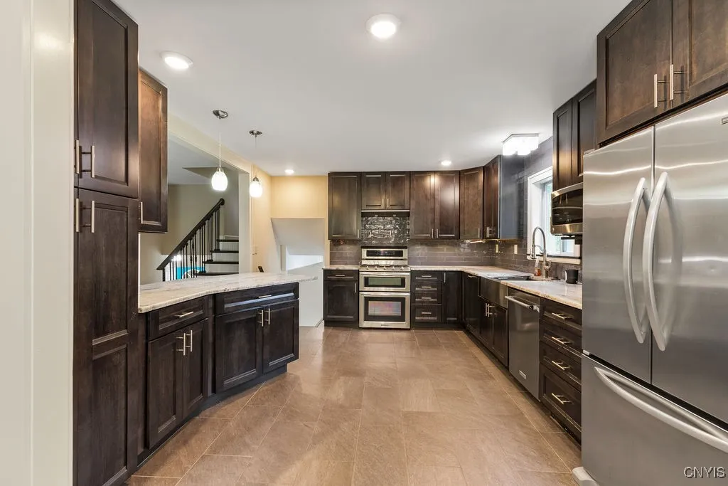 This view of the kitchen shows a tall pantry cupboard to the left, the breakfast bar, and plenty of room to move around while preparing meals.