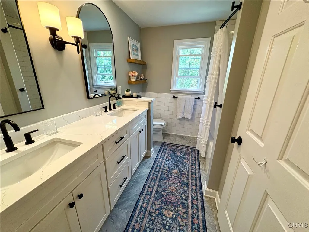 Remodeled bathroom with double sinks and tiled shower.