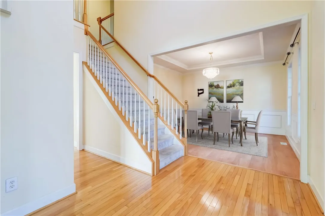 Sophicated dining room with tray ceiling and wainscoting welcomes your guests (virtually staged)