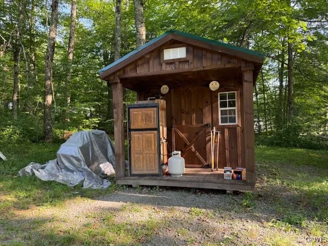 Tiny cabin with propane refrigerator on porch.
