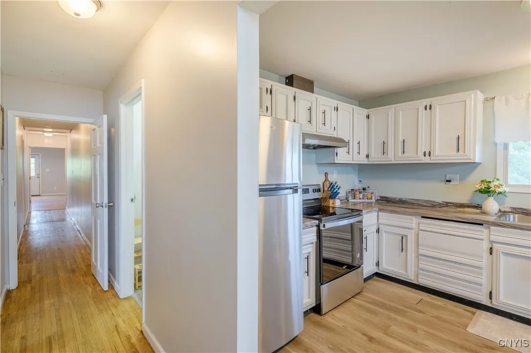Kitchen with stainless steel appliances and a fresh clean feel with bright white cabinetry and a hallway leading to the Bedrooms!