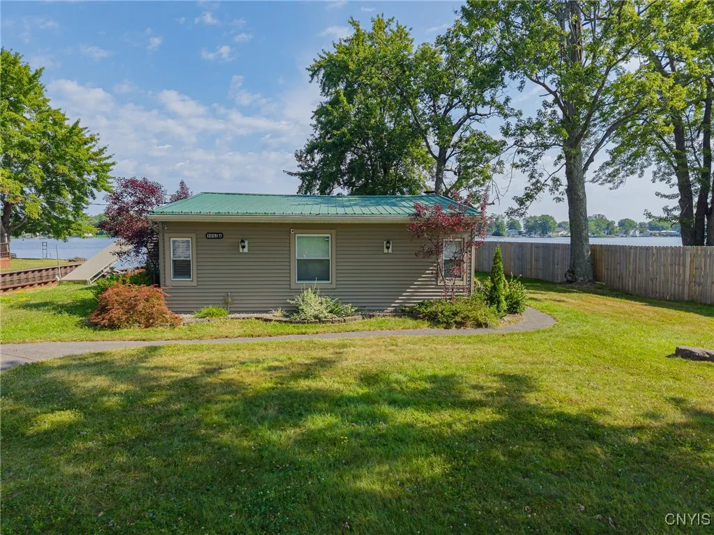 A view of the back of the house from the roadside.  This lot has nice, flat yards both in front and in back and several shade trees create more spots around the house to relax in!
