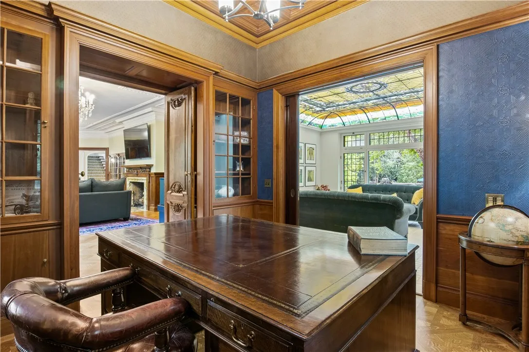 A handsome home office features a coffered curly cherry ceiling, built-in bookcases, leaded windows, and mahogany pocket doors.