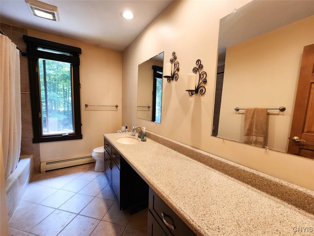 The second upstairs bathroom features neutral tones, plenty of storage and counter space and a bathtub.