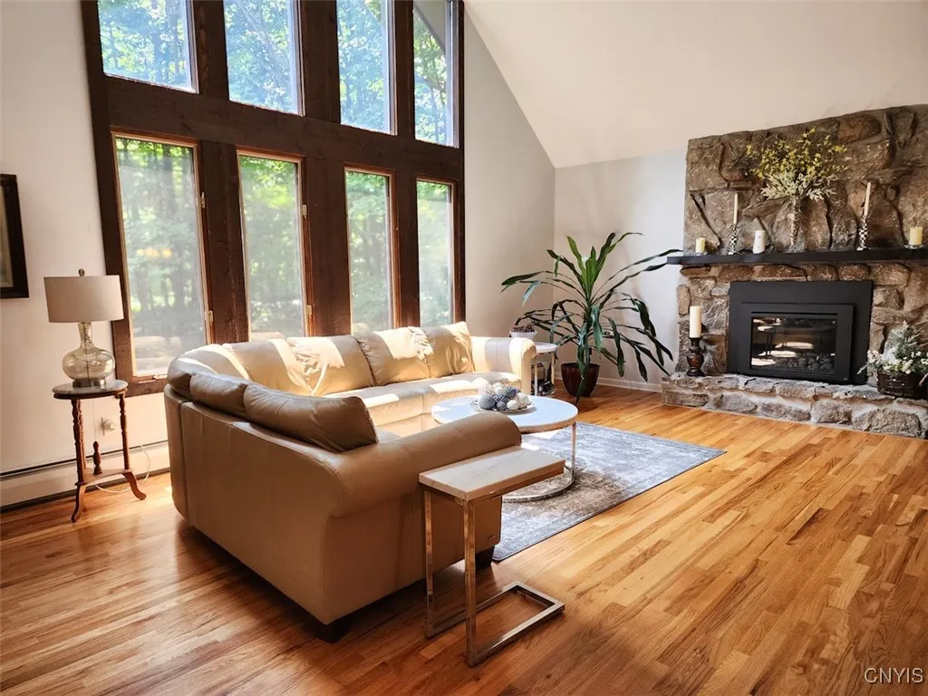 When you enter the home, you walk up a short flight of stairs into this stunning Great Room. It features expansive windows, a gorgeous stone fireplace, and beautiful hardwood floors.