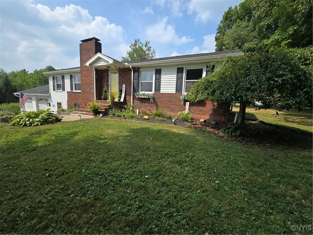 Sitting a little higher than the front of the land, the brick facade stands out against the white background and black shutters. The yellow door gives a pop of color.