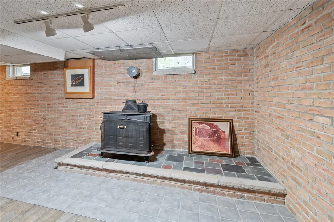 The WOOD BURNER in the finished lower level space - the 200 amp UPDATED ELECTRIC panel box is behind the picture with the cork board background