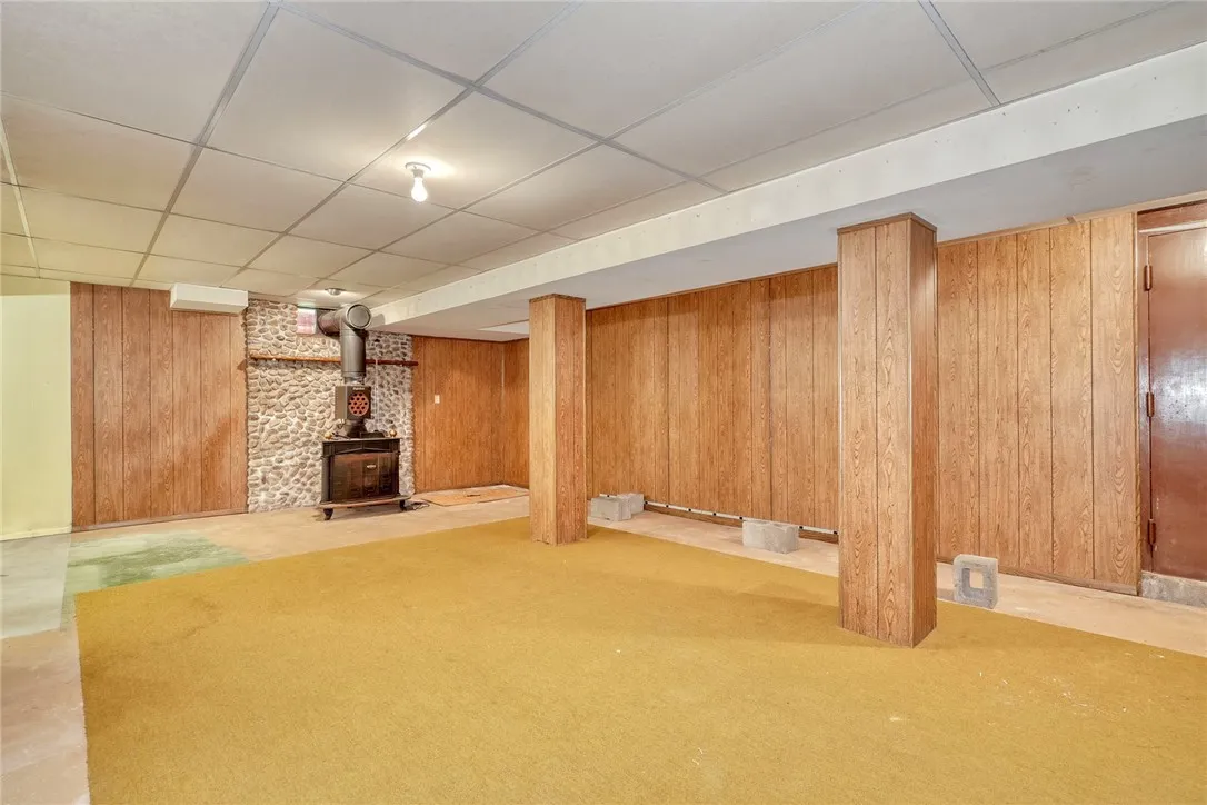 part-finished basement with wood stove and cobblestone wall