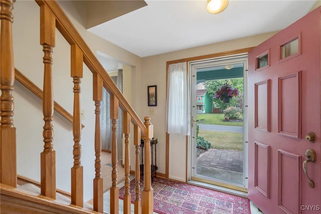 Now we enter the home, stepping into the front foyer. The center hallway design leads into the kitchen & garage behind us, or into the formal living room through the doorway to the left here. The spindled banister stairs lead to the bedroom level, which we will explore later in the tour.