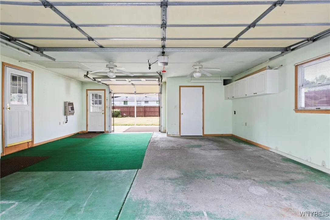 two plus heated garage with rear garage door opening to covered concrete patio plus enclosed storage/workshop area