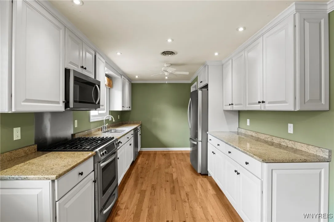 bright kitchen with can lighting stainless gas stove, microwave and dishwasher