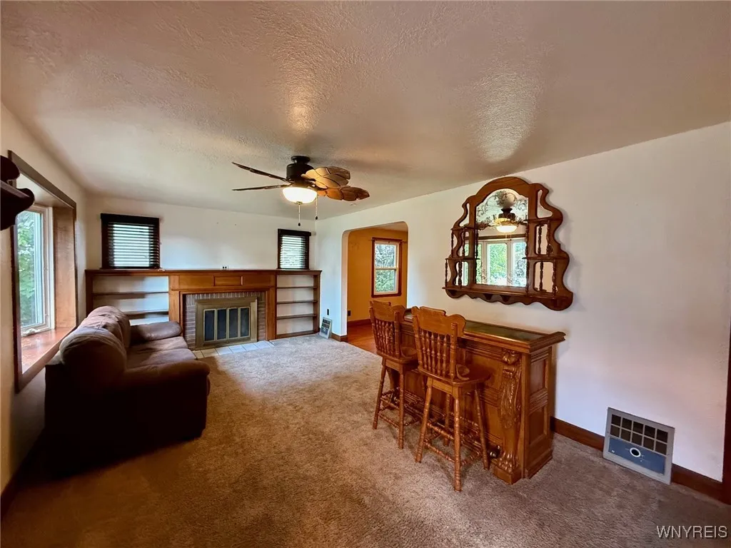 Spacious living room showcasing rich natural woodwork and a custom-built wood-burning fireplace mantle—perfect for cozy evenings.
