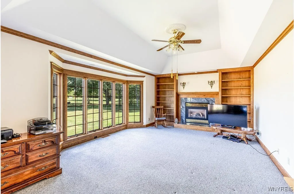 Large rear family room with tray ceiling, gas fireplace and built-in shelves