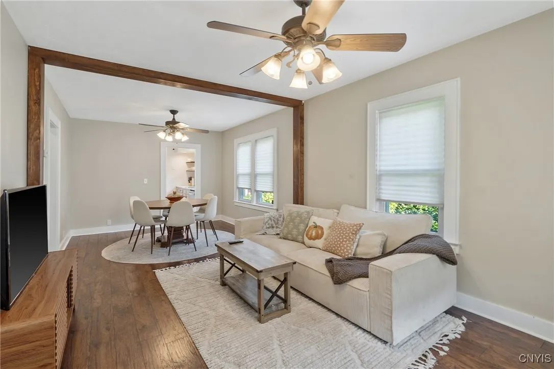 The view from the front door shows how the space continues into a formal dining area with a wood beam separator which offers depth and contrast to define each room.  Overhead lighting with fans in both side are a smart touch to keep the heating or central air moving depending on the season.