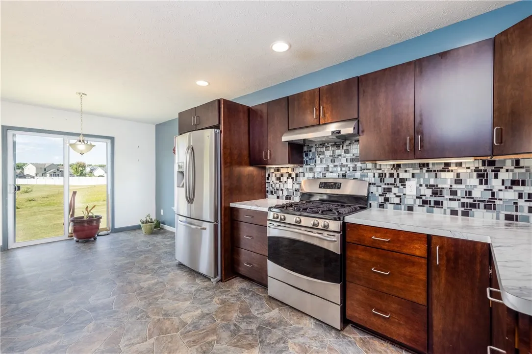 BEAUTIFUL EAT IN KITCHEN WITH CUSTOM CABINETRY, STAINLESS STEEL APPLIANCES WITH BACKYARD VIEWS VIA SLIDING GLASS DOOR.