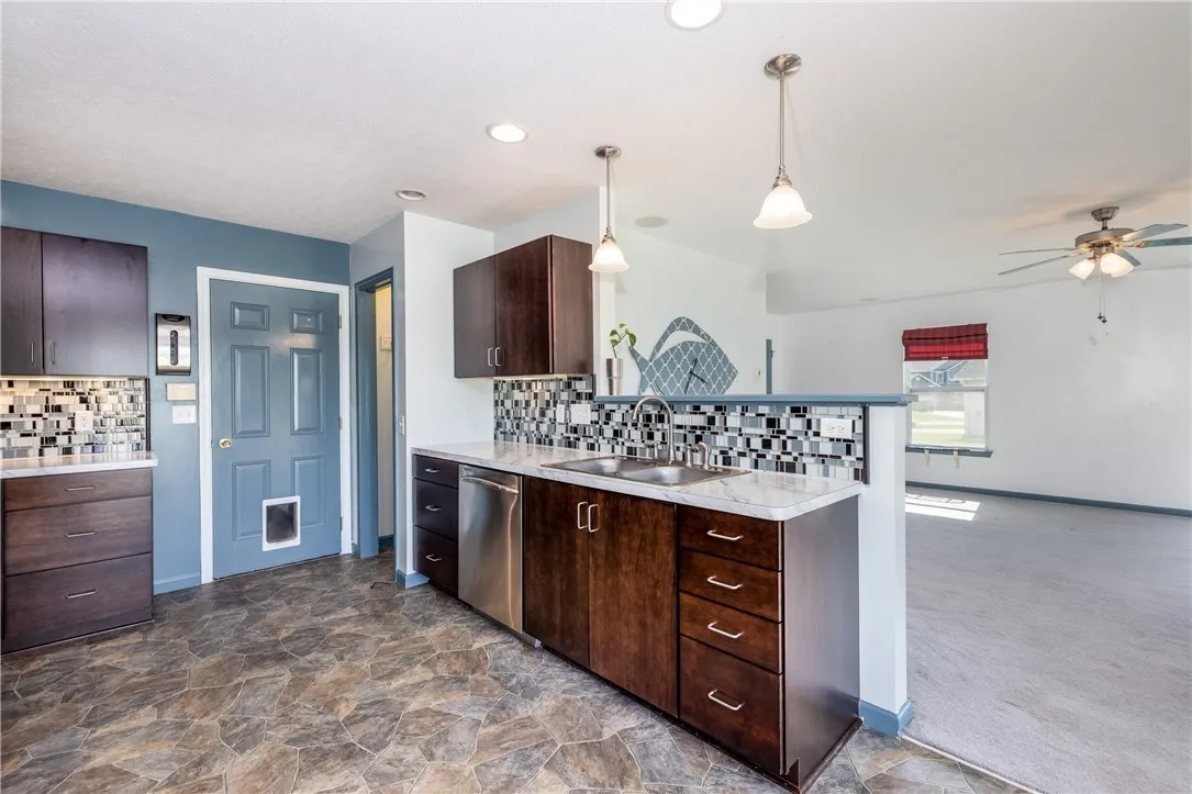 BEAUTIFUL EAT IN KITCHEN WITH CUSTOM CABINETRY, STAINLESS STEEL APPLIANCES WITH BACKYARD VIEWS VIA SLIDING GLASS DOOR.