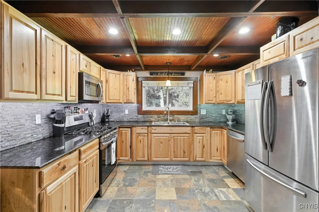 Stepping into the large kitchen, you are sure to be impressed by the hickory cabinetry, granite countertops, new backsplash, tile floors, and gleaming stainless steel appliances. And look at that stunning wooden ceiling!