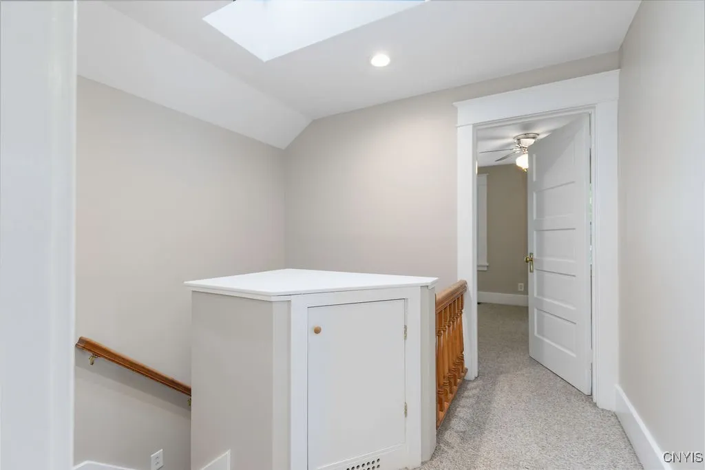 The space at the top of the stairs includes a storage cabinet, skylight, and recessed lighting.