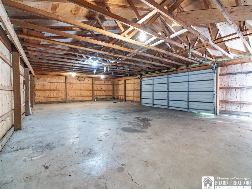 Interior view of the detached garage with overhead door and cement slab floor.