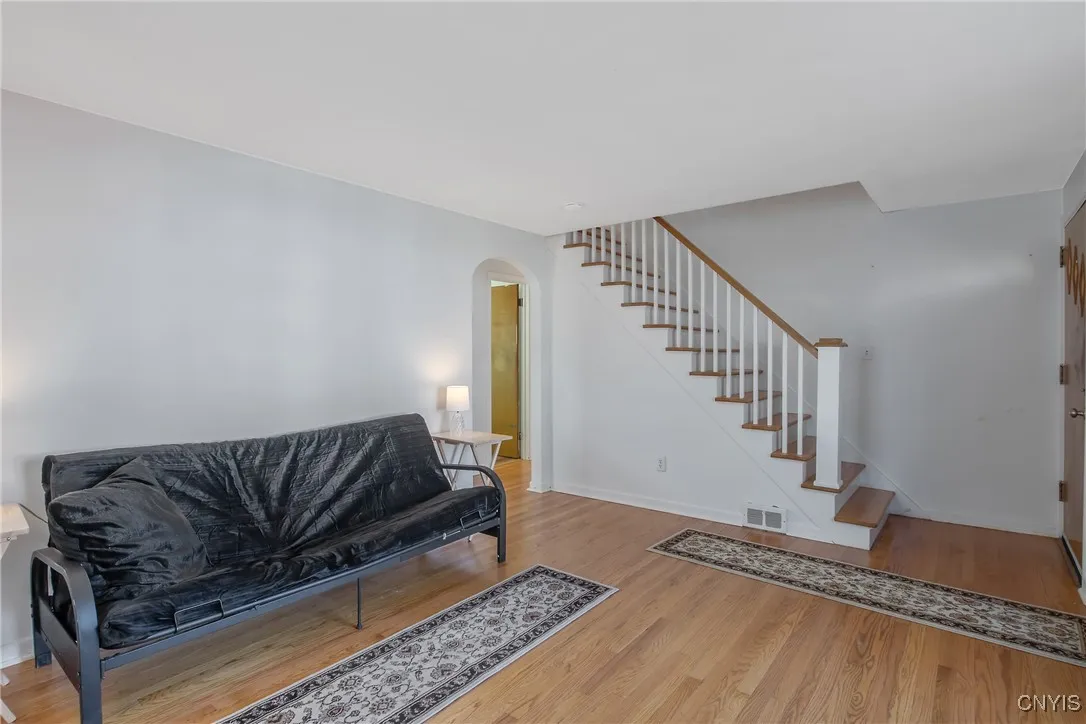 This is the living room looking towards front entrance and staircase, note arched entrance to kitchen and hallway