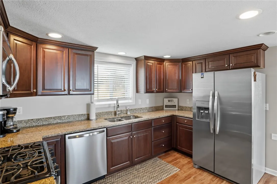 Modern kitchen with granite counters, stainless appliances, and rich cabinetry