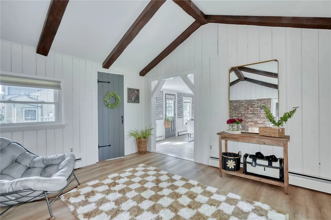 Vaulted bonus room with beams, brick wall, and slider to deck- Flexible uses!! Perfect for office, mudroom, or sitting room.
