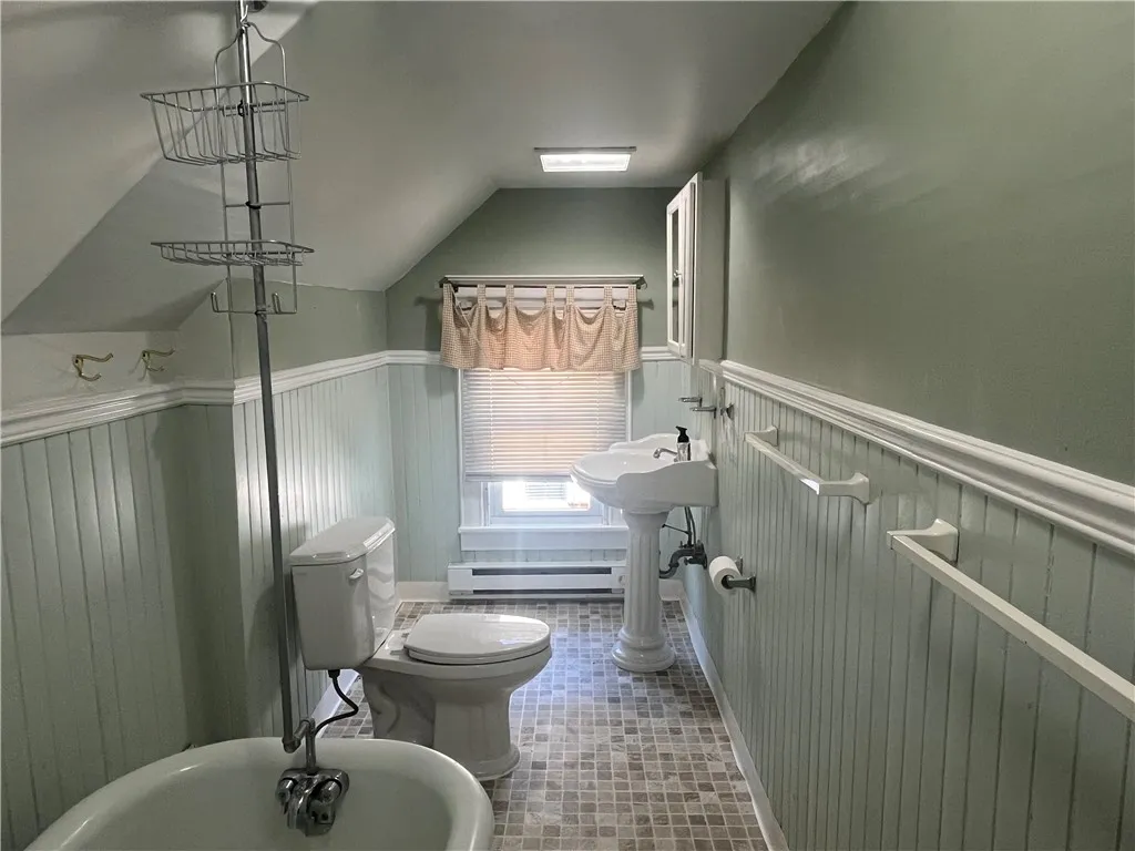 Full Bath features wainscoting, new flooring & white fixtures