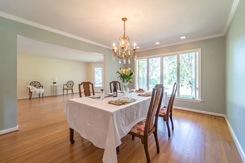 The living room flows seemlessly into the dining room enhanced by crown molding, a large window, and a built-in custom buffet with cabinets and drawers.
