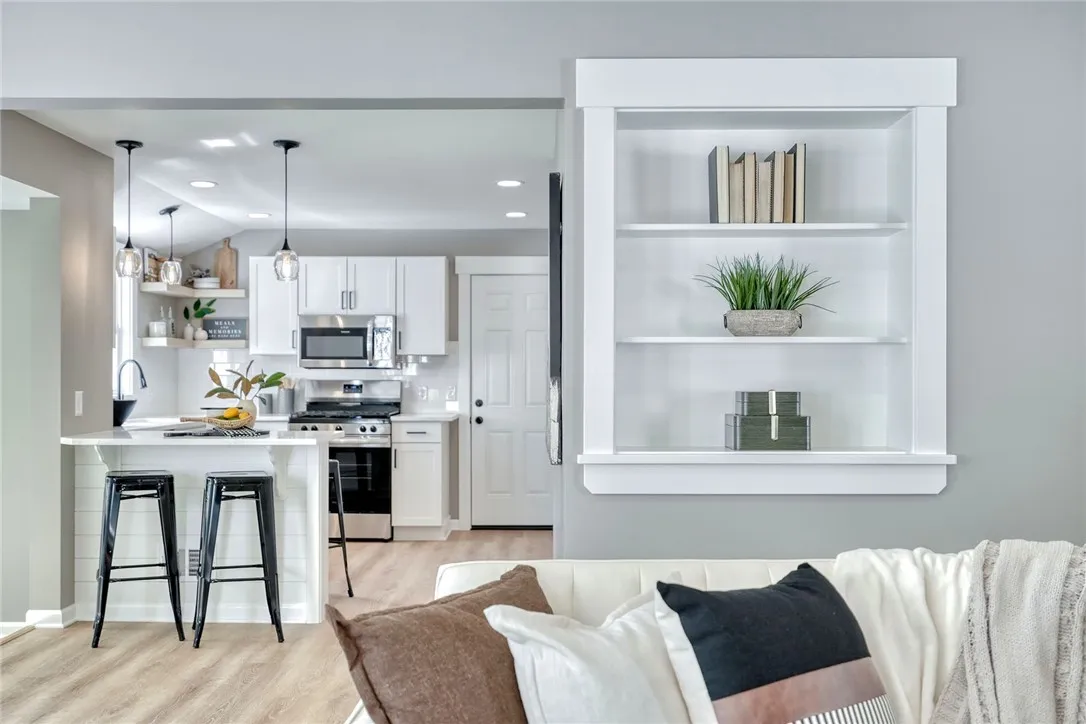 Bright, modern kitchen with quartz countertops, stainless appliances, and open shelving.