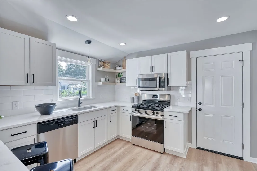 Bright, modern kitchen with quartz countertops, stainless appliances, and open shelving.