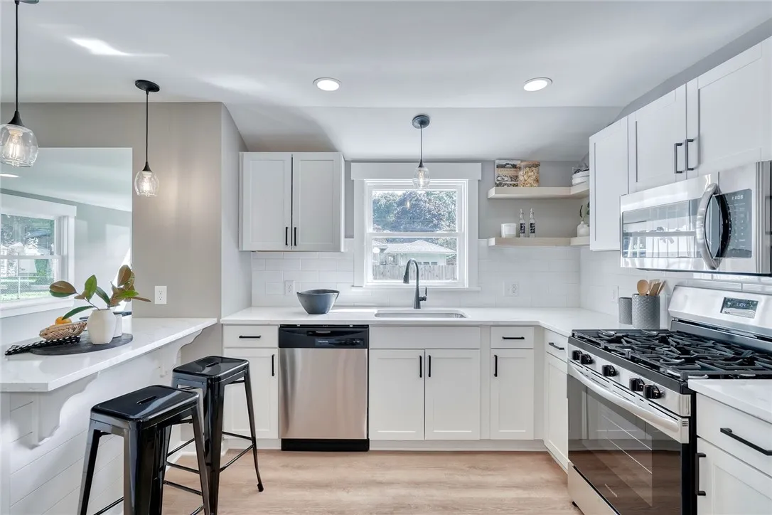 Bright, modern kitchen with quartz countertops, stainless appliances, and open shelving.