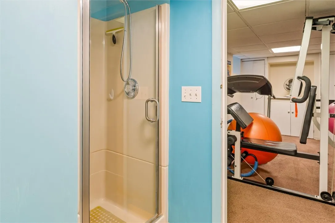 basement full bathroom with view into bonus room/gym