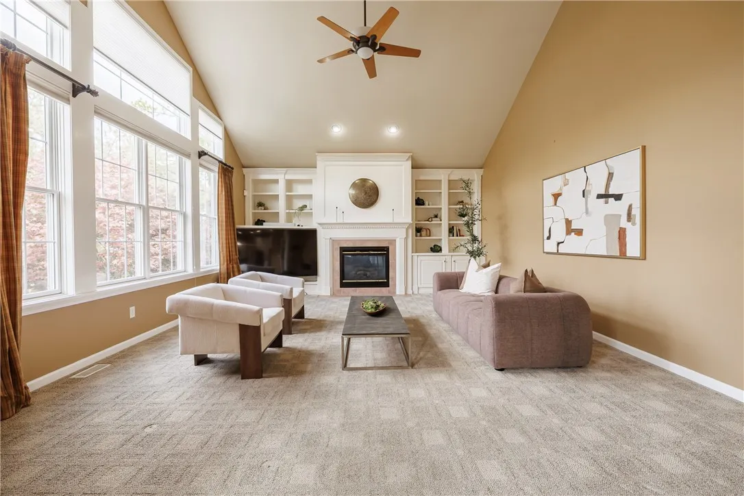Huge, bright family room with built-ins, cathedral ceiling, enormous windows, and a gas fireplace to cozy it up! The large mounted TV and built-in, house-wide Sonos system will convey with the house!